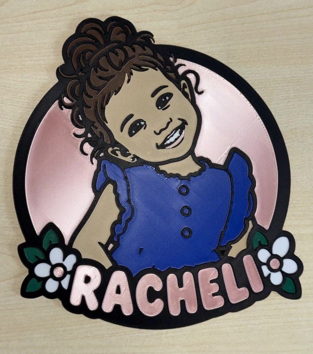 Portrait d'enfant personnalisé imprimé en 3D d'après une photo : fillette aux cheveux bouclés en robe bleue, avec son prénom et des fleurs